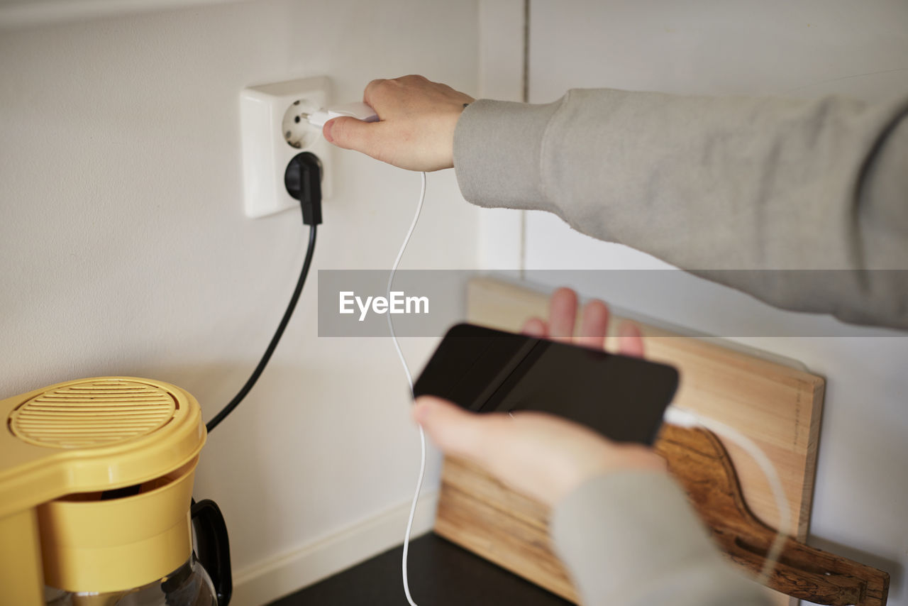 Hands plugging in cell phone charger