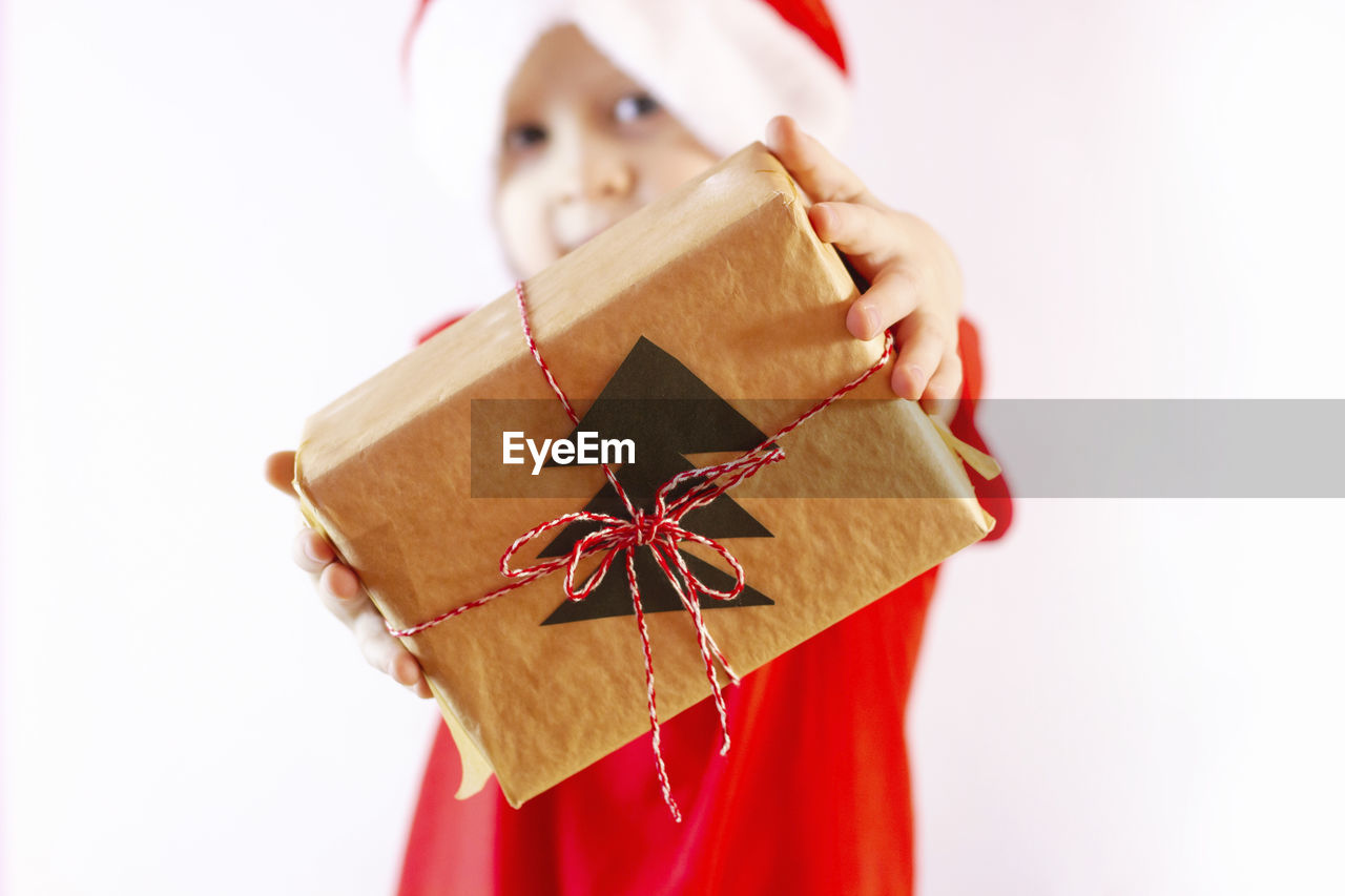 gift, christmas, celebration, box, holiday, red, one person, holding, paper, surprise, emotion, child, childhood, event, indoors, white background, gift box, christmas decoration, giving, tradition, happiness, studio shot, container, bow, cute, ribbon, wrapped, present, decoration, clothing, cardboard, tied bow, hat, men, wrapping paper, portrait, copy space, nature, positive emotion