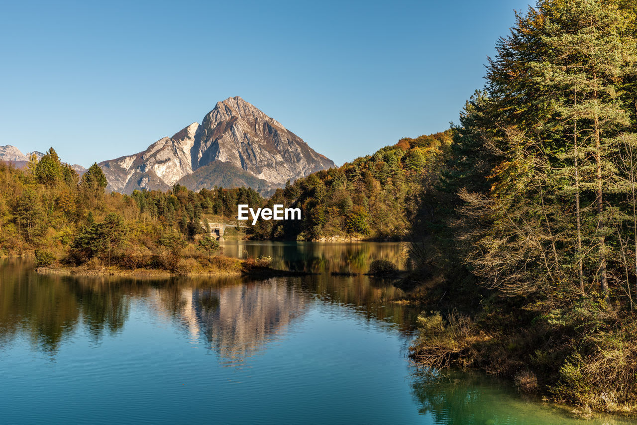 Scenic view of lake and mountains against clear blue sky