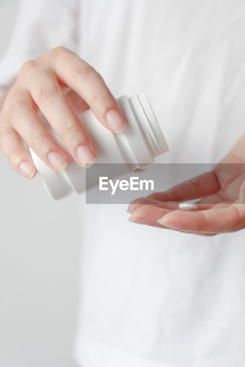 Close up of female hands pouring medicine tablets from bottle into her hand