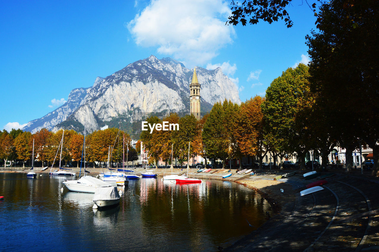 Boats in lake by trees against sky