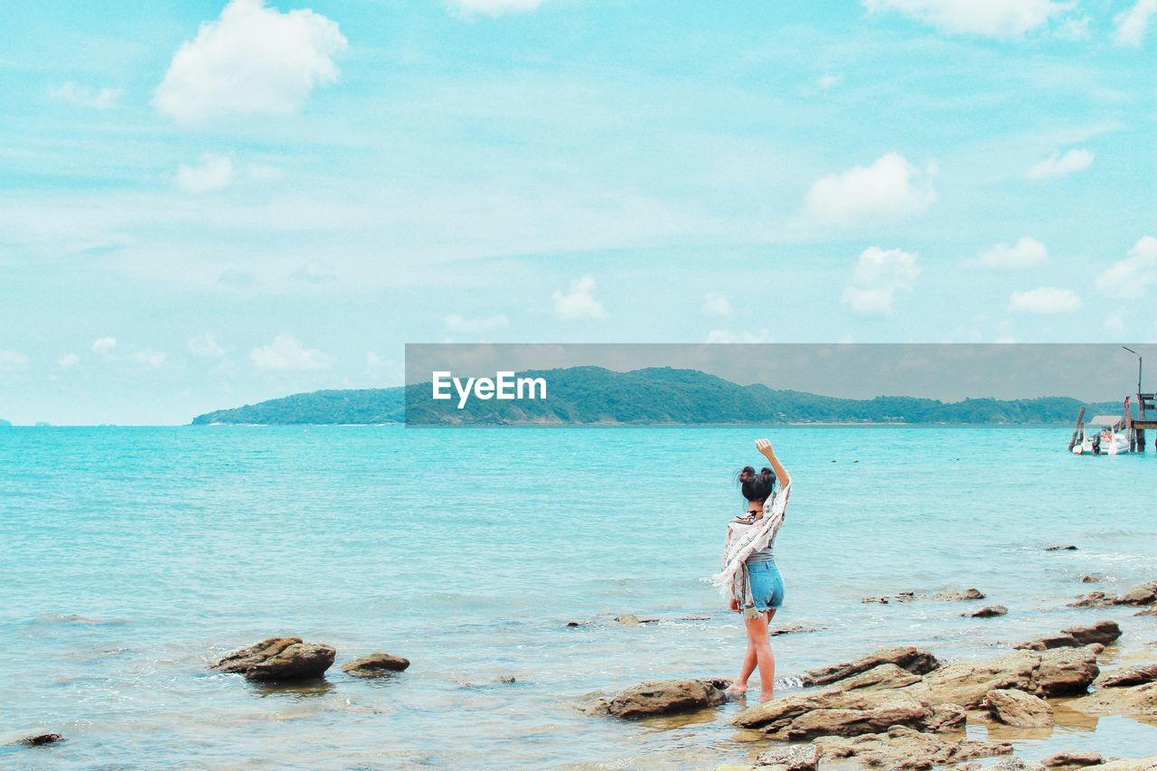 Full length of woman standing on beach against sky