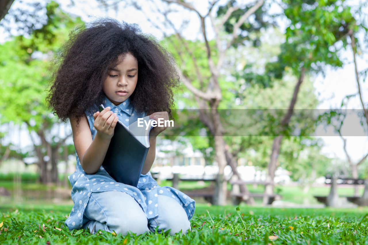 Girl reading book on field