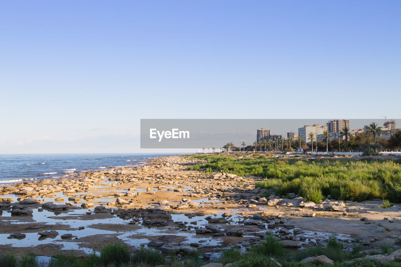 buildings by sea against clear sky