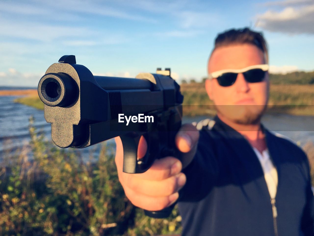 Man holding gun by lake