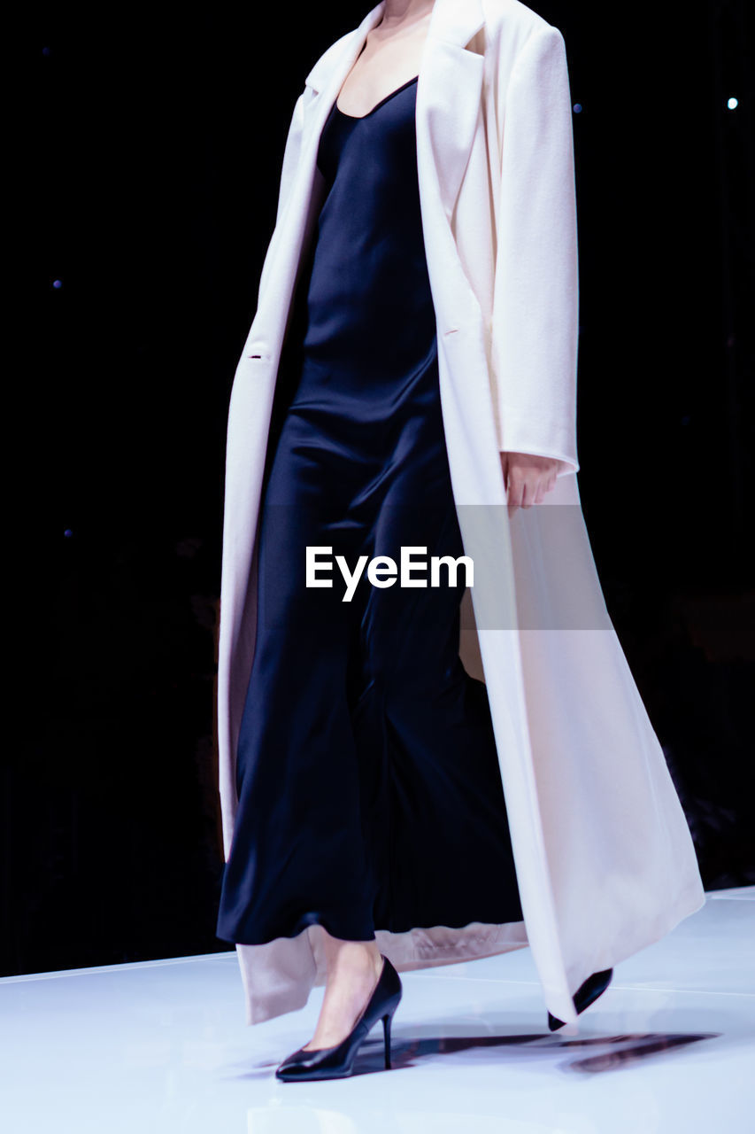 Fashion details of a white coat, black silky dress and high heels. women's fashion and accessories.