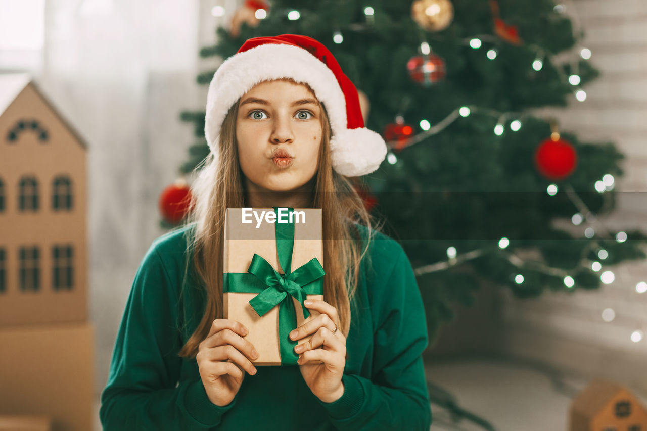 A beautiful girl with surprised eyes looks at the camera with a gift from kraft paper 