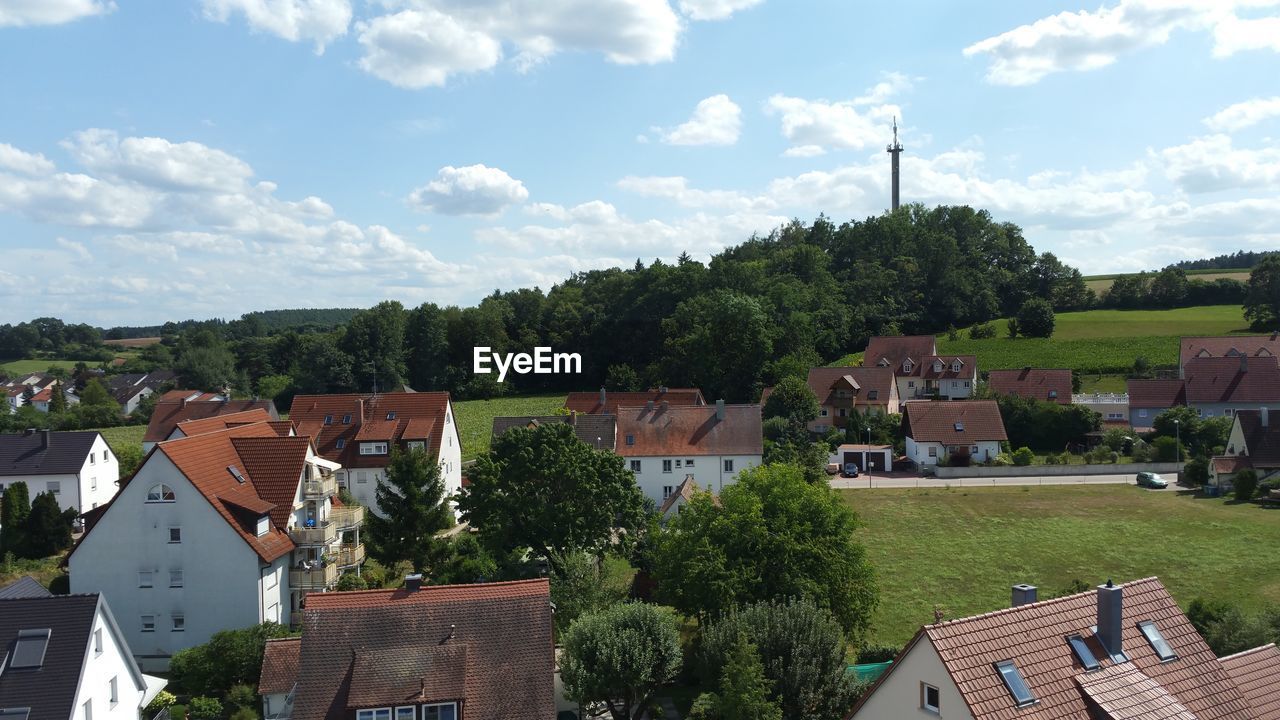 HIGH ANGLE VIEW OF TOWNSCAPE AND TREES AGAINST SKY