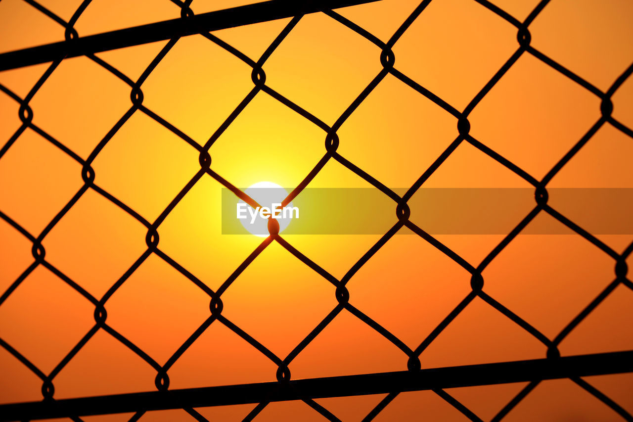CLOSE-UP OF CHAINLINK FENCE AT SUNSET