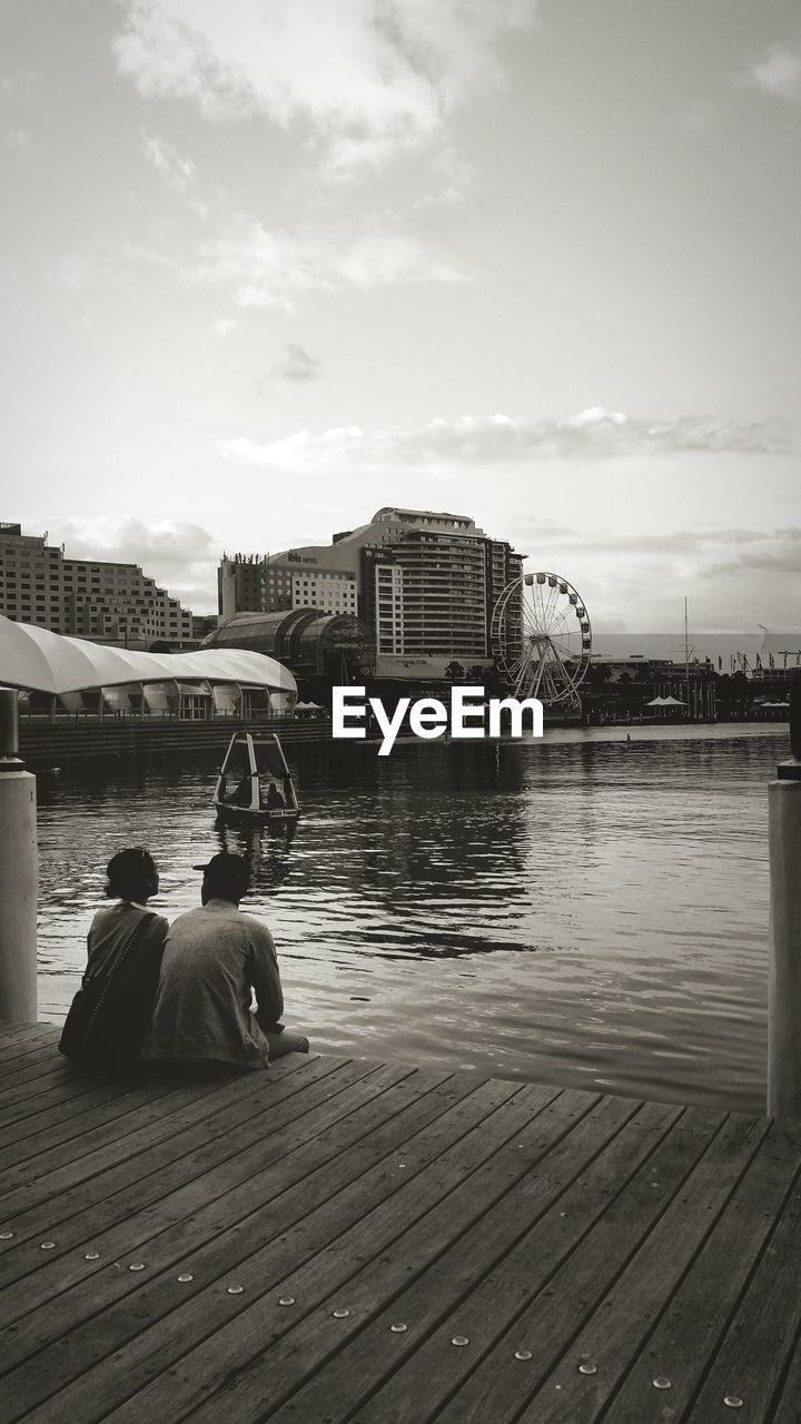Couple sitting on pier at sea