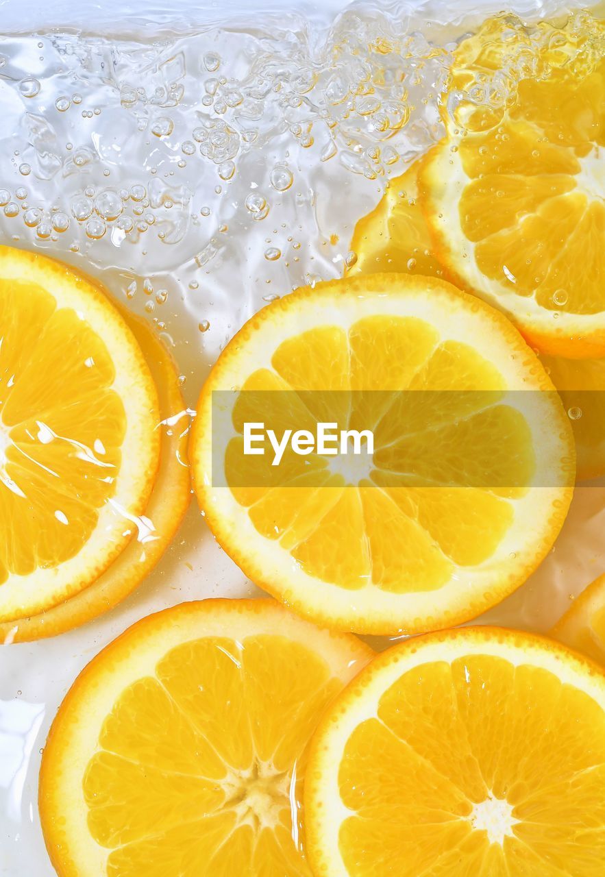 Close-up fresh slices of juicy orange on white background. slices of orange in sparkling water.