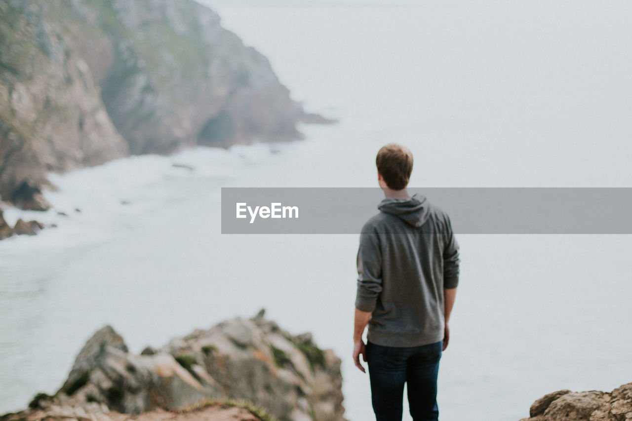 Rear view of man standing against sea