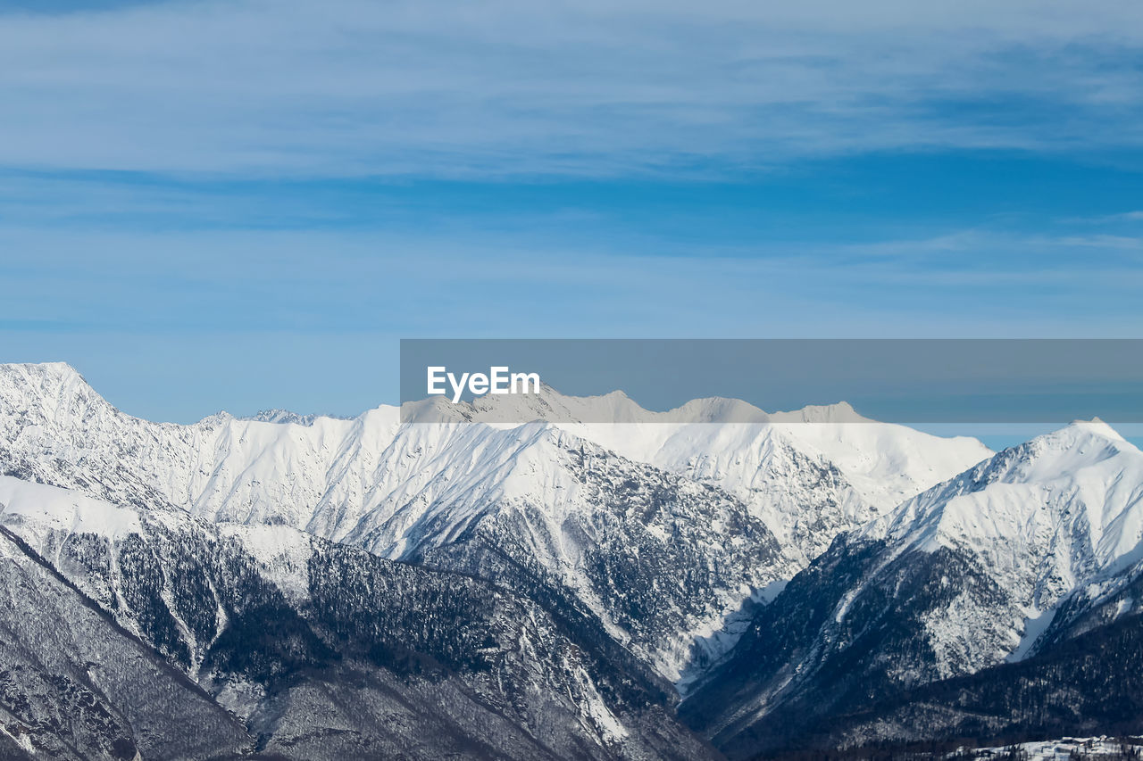 Snowy mountain ranges on the background of the blue sky with clouds. the lower part of the mountains 