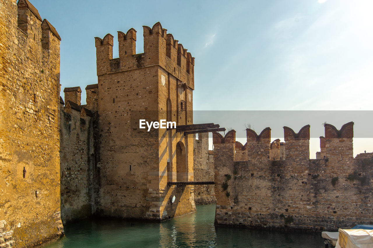 Old building by river against sky