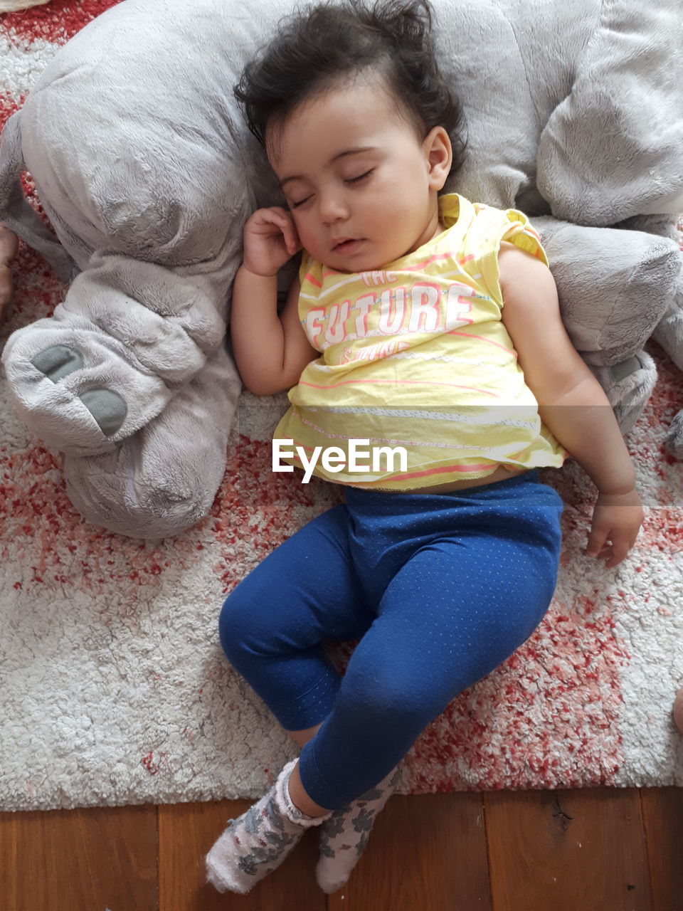 High angle view of baby sleeping with toy on rug at home