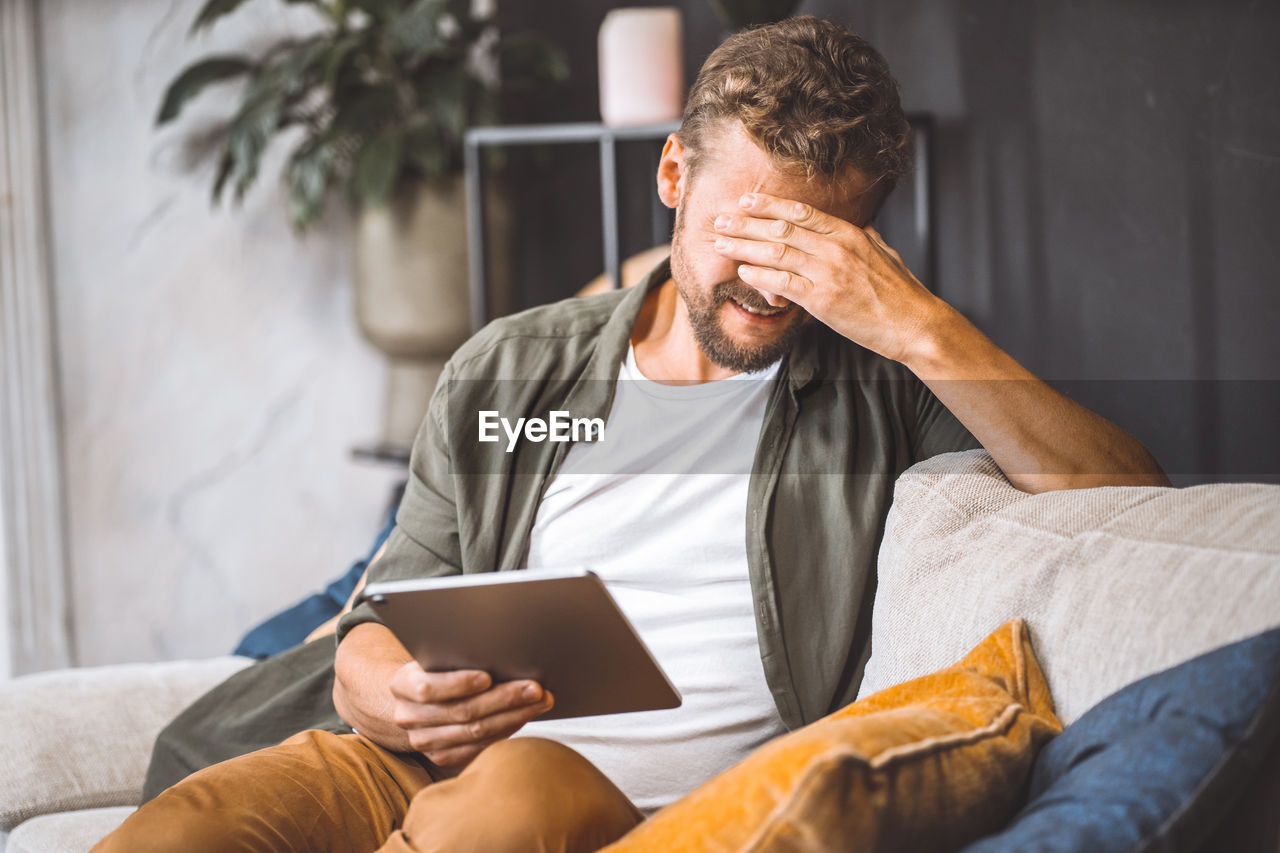 young man using mobile phone while sitting at home