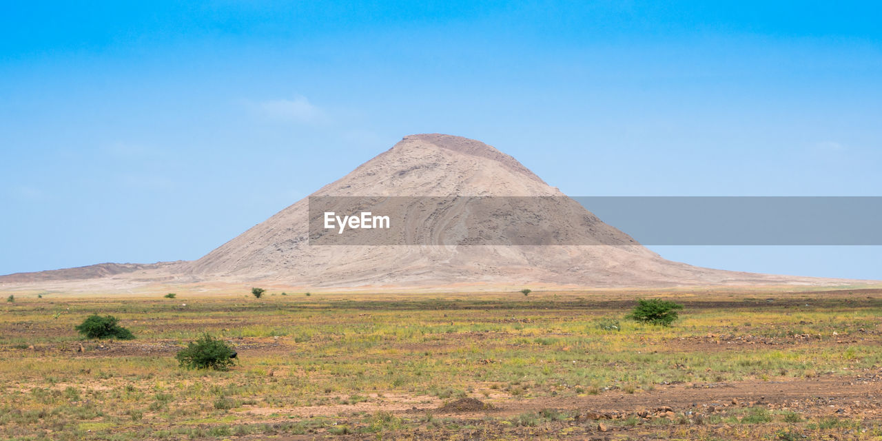 Scenic view of land and mountain against sky