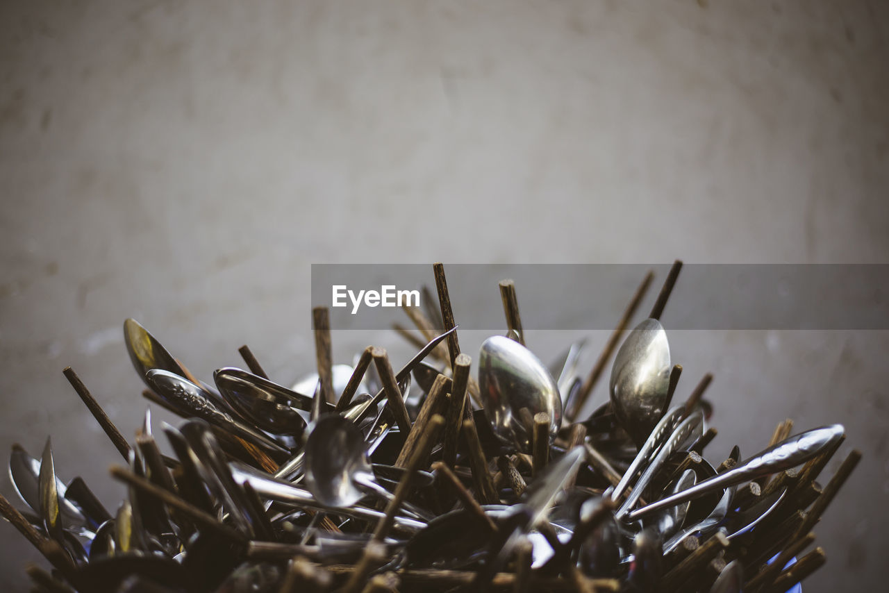 Close-up of chopsticks and spoons against wall