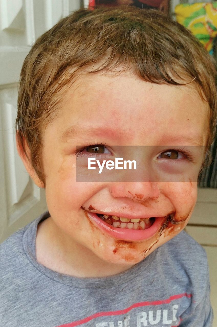 Portrait of playful boy with chocolate on face at home
