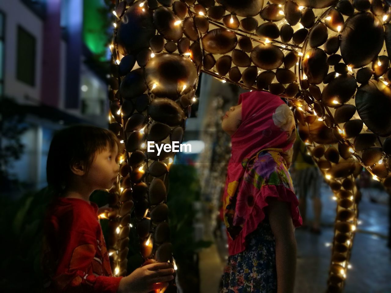 Girls standing by illuminated decoration at night