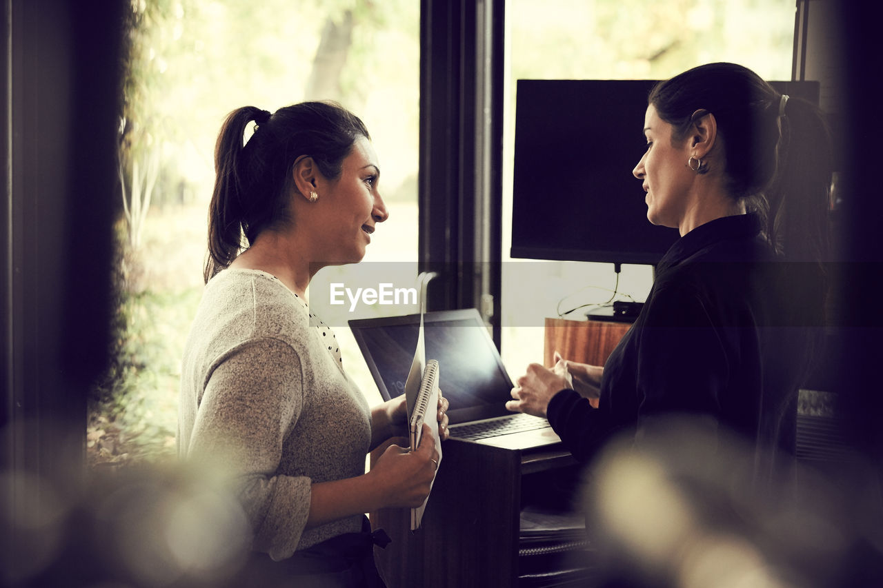 Female owner talking to customer about order while standing in cafe