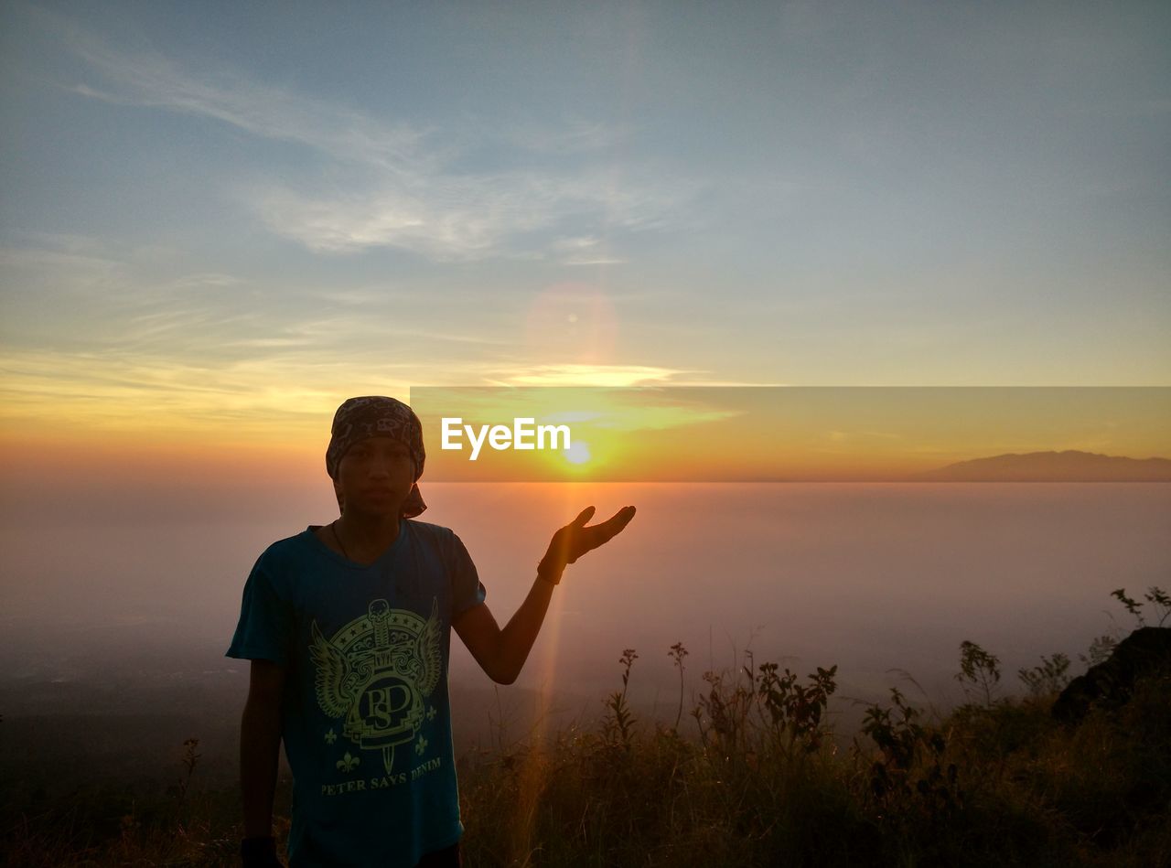 MAN STANDING AGAINST ORANGE SKY