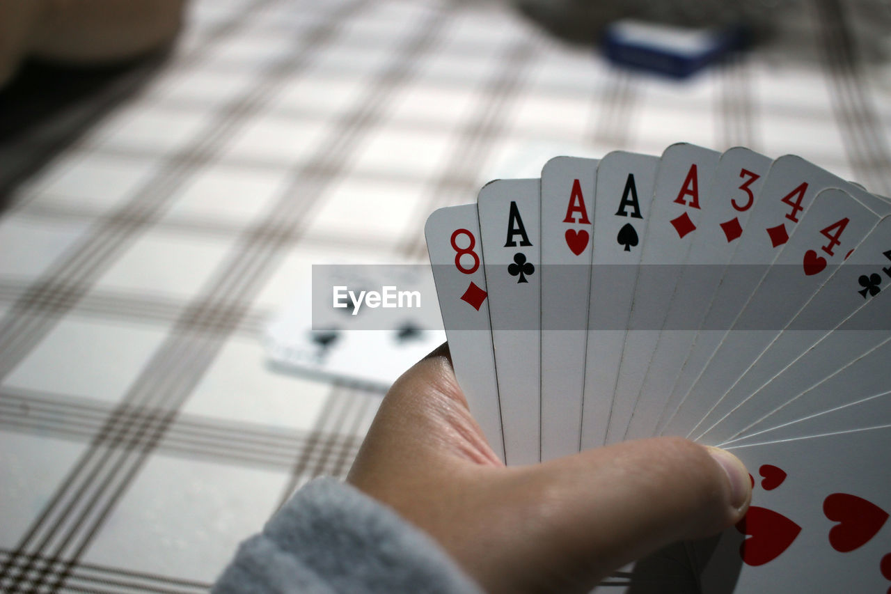 Close-up of hand holding playing cards on table