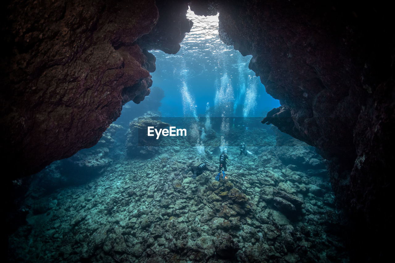 High angle view of people swimming amidst rock formations in sea