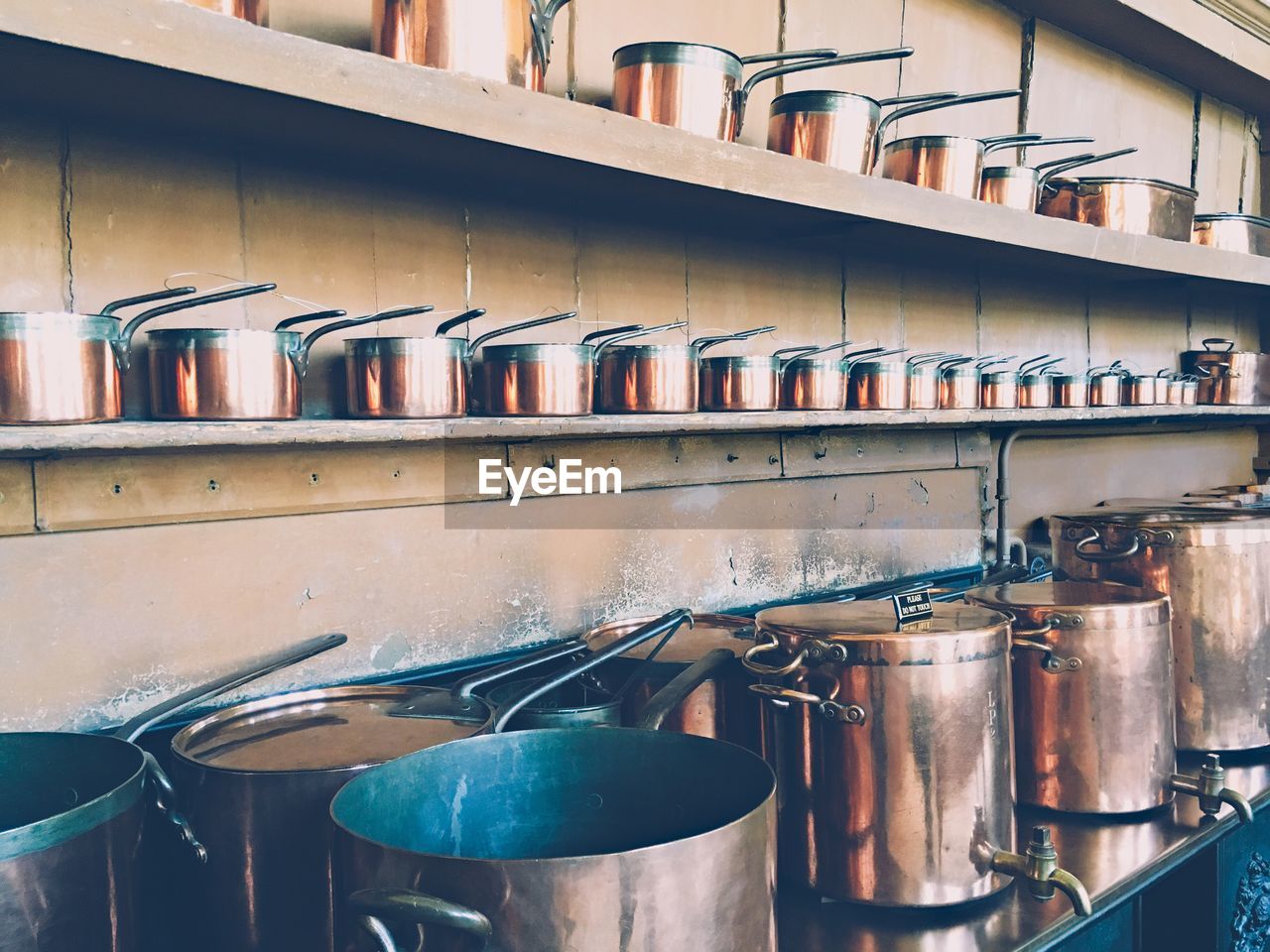 Copper utensils arranged on shelf in kitchen