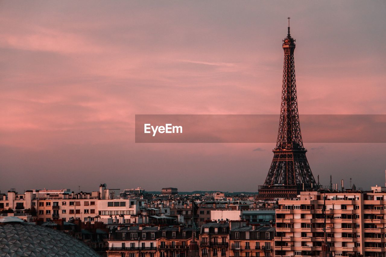 Eiffel tower amidst buildings against sky during sunset