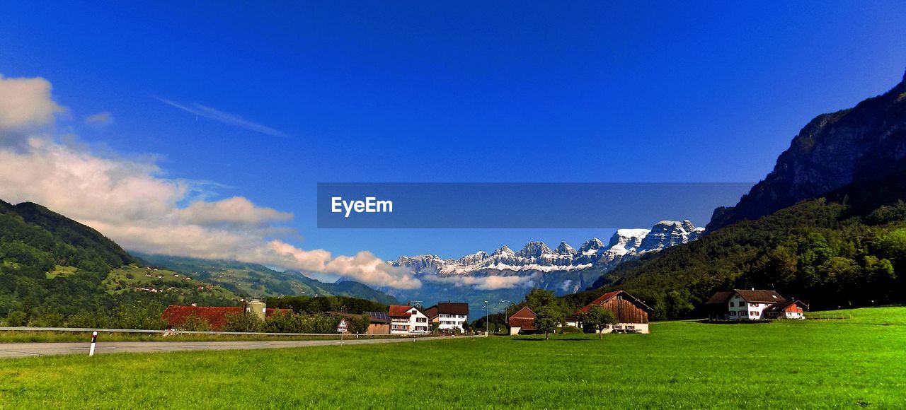 Houses on field with mountain range in background