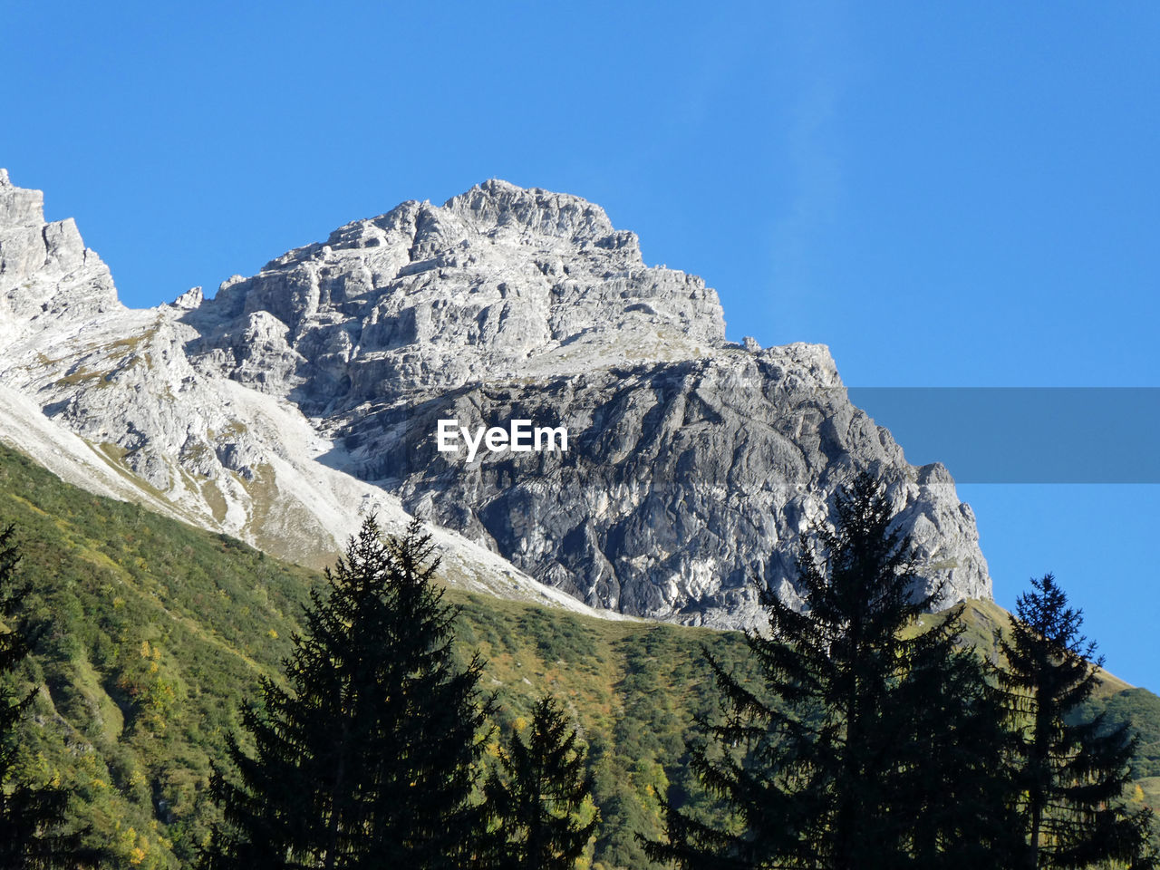 Low angle view of snowcapped mountains against clear blue sky