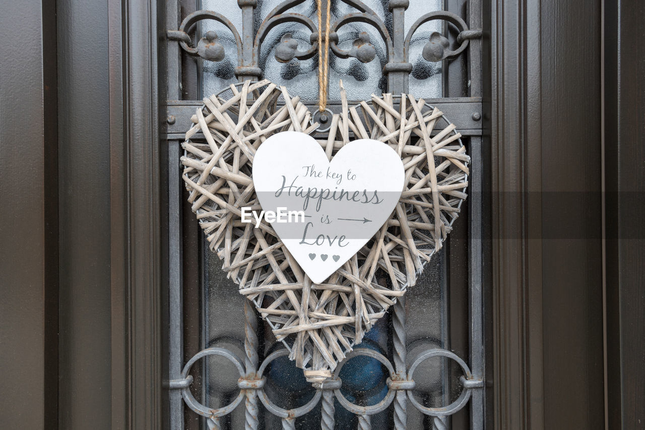 A wicker heart hanging on the door with happiness and love quote