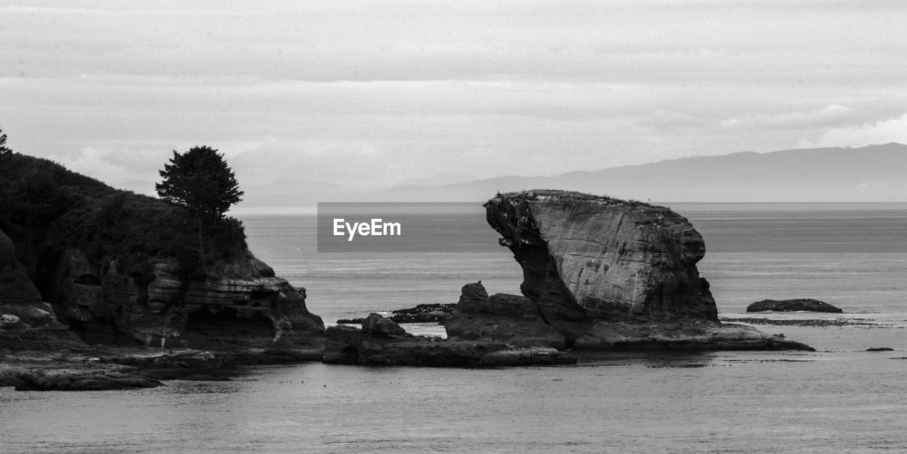 Scenic view of rocks on sea against sky