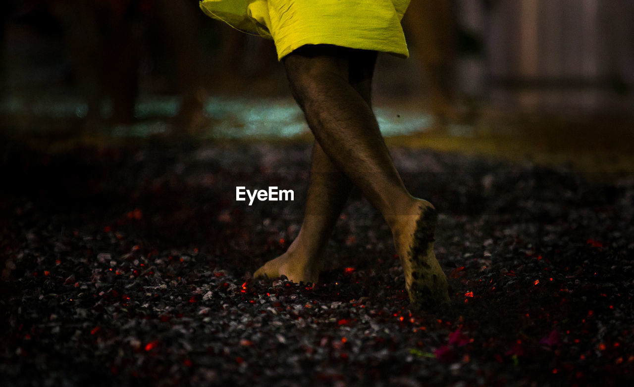Low section of man running barefoot on hot coals
