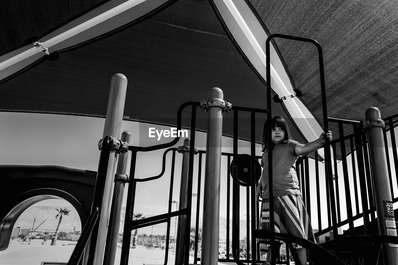 Low angle view of girl standing by railing at playground