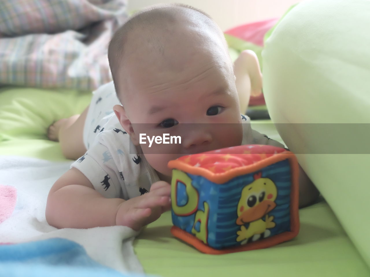 CLOSE-UP OF BABY BOY PLAYING WITH TOY ON BED