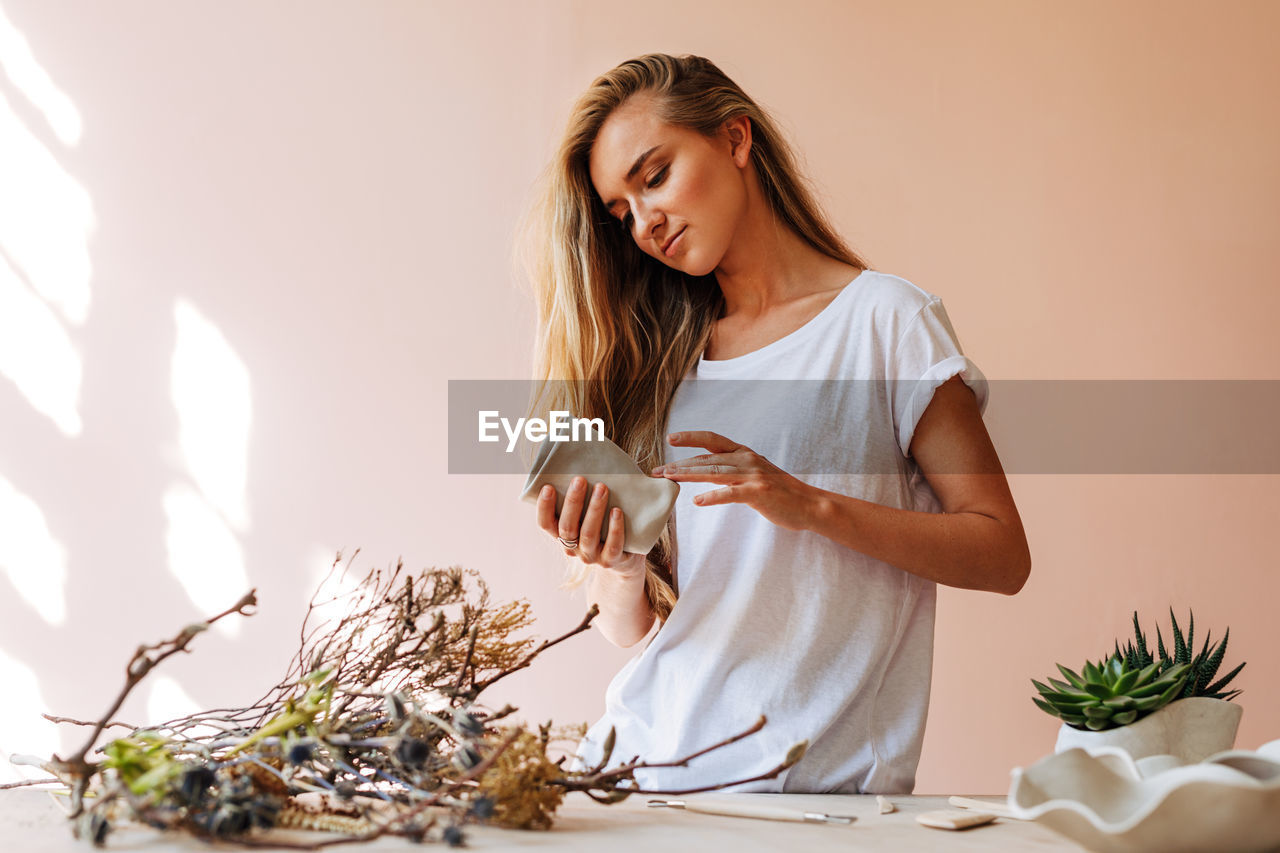 Young woman looking away while molding a shape on table