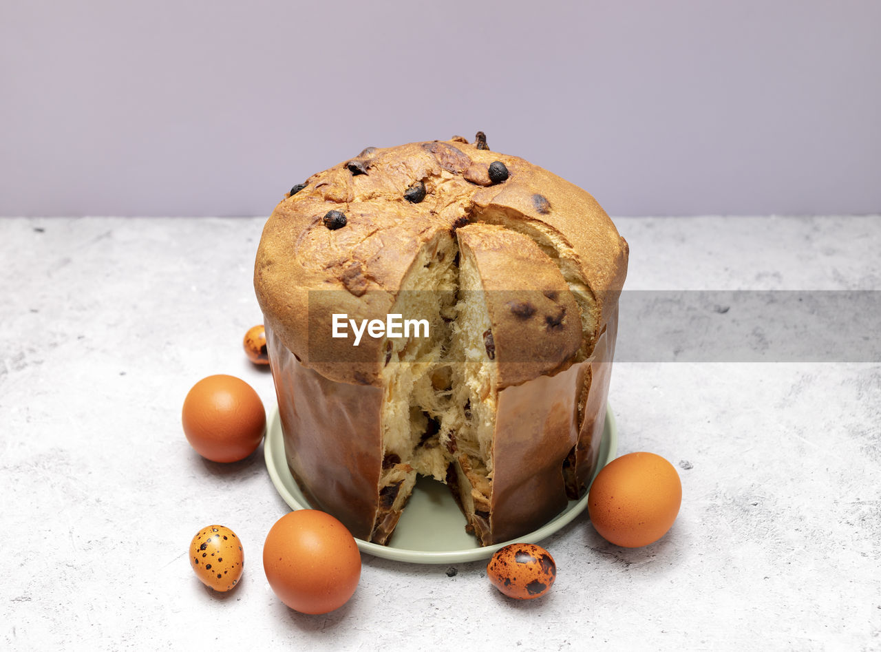 Easter panettone italian cake on table with colored easter hen eggs. fruitcake, sweet bread