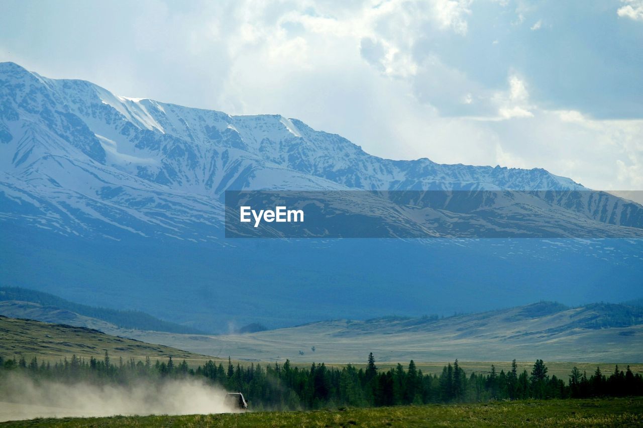 Tranquil view of landscape and mountains against cloudy sky