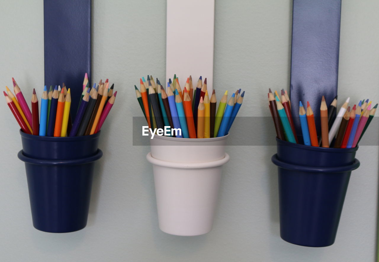 Colored pencils in containers on wall