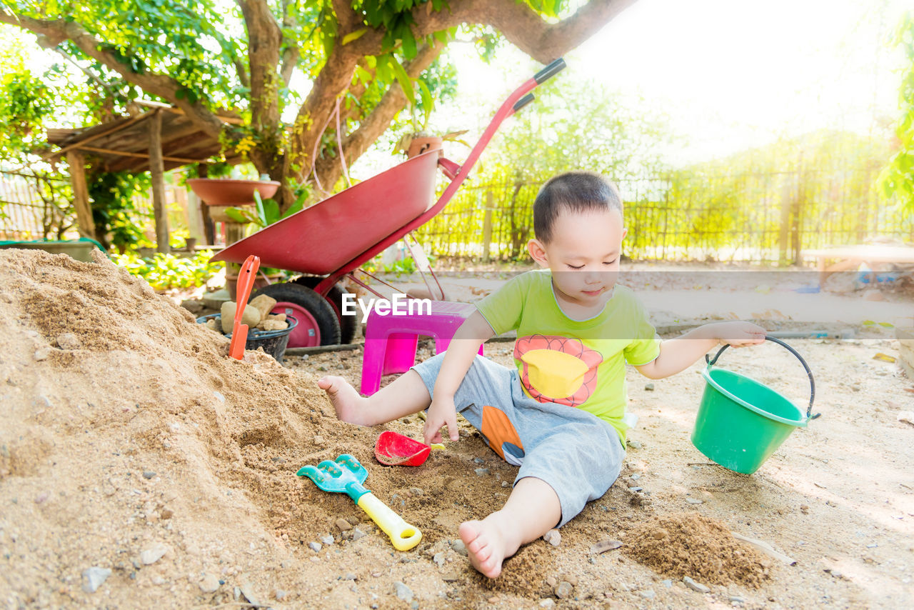Boy playing with toy on sand outdoors