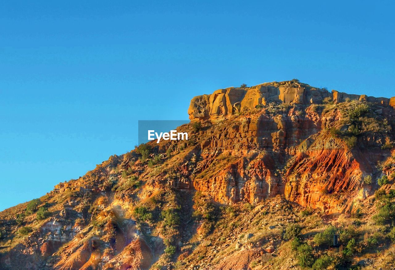 Low angle view of rock formation against clear blue sky