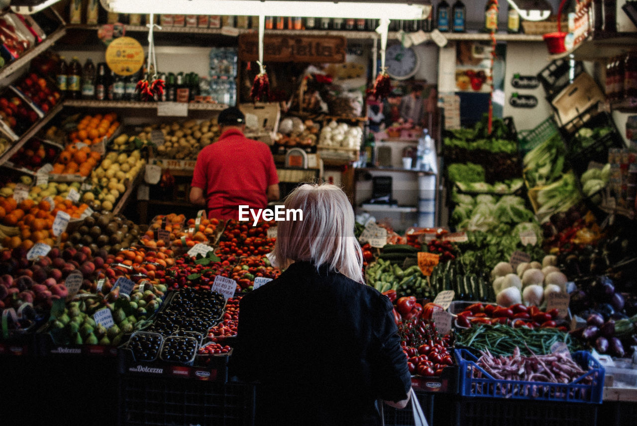 REAR VIEW OF WOMAN WITH FRUITS AT MARKET STALL