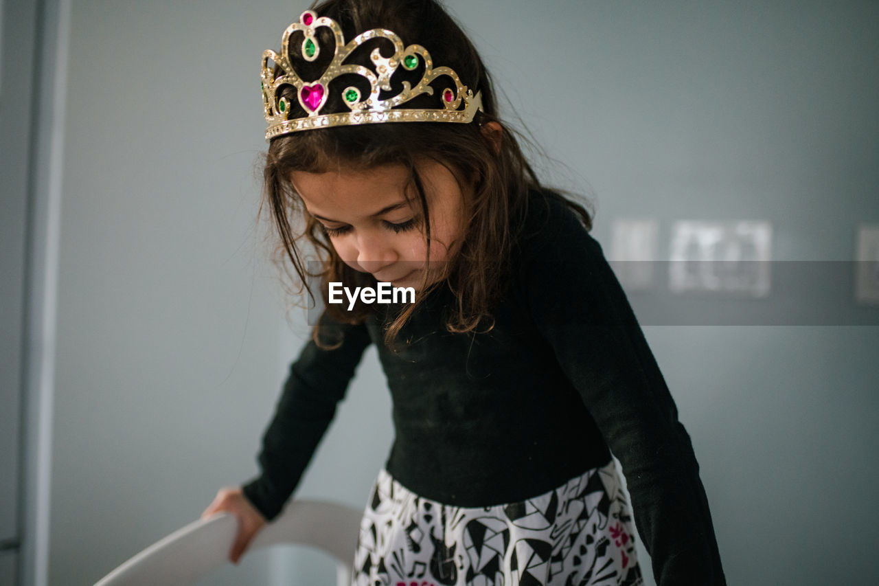 4 year old girl wearing tiara looking down