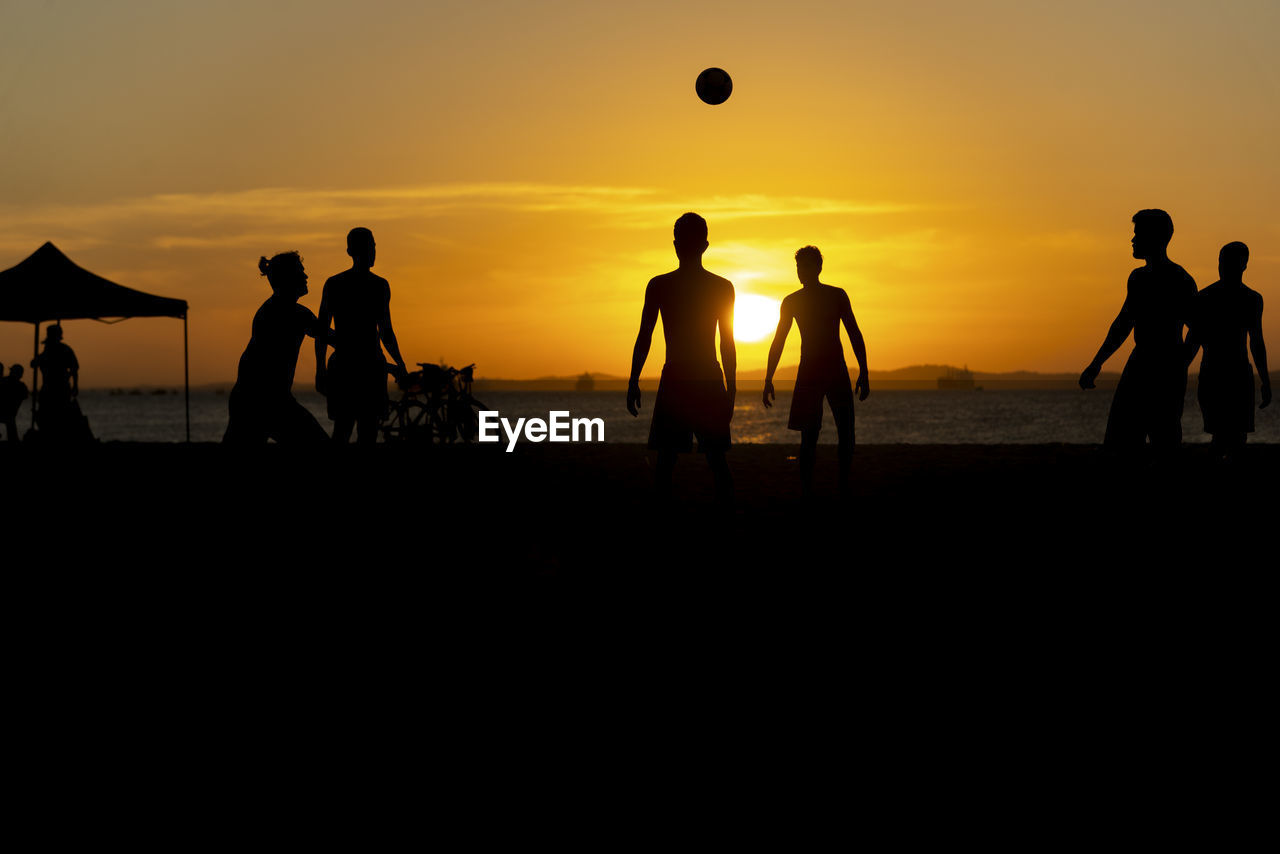  young people playing beach soccer during sunset at ribeira beach in salvador, bahia, brazil.