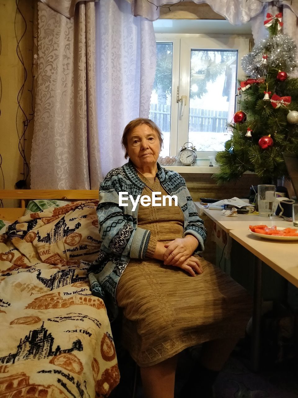 PORTRAIT OF SMILING WOMAN SITTING AT HOME