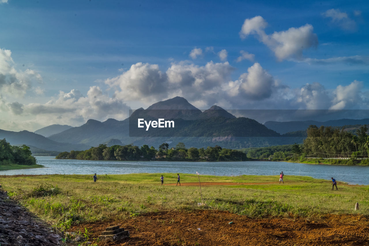 Scenic view of field by river against sky