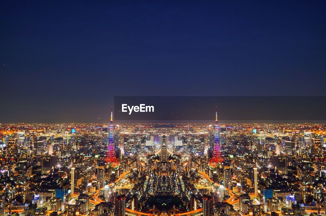 High angle view of illuminated cityscape against clear sky at night