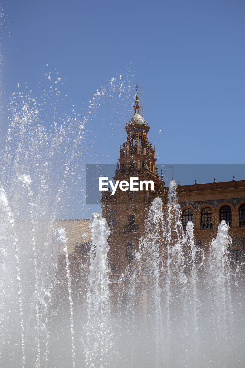 Fountain in front of building against clear sky